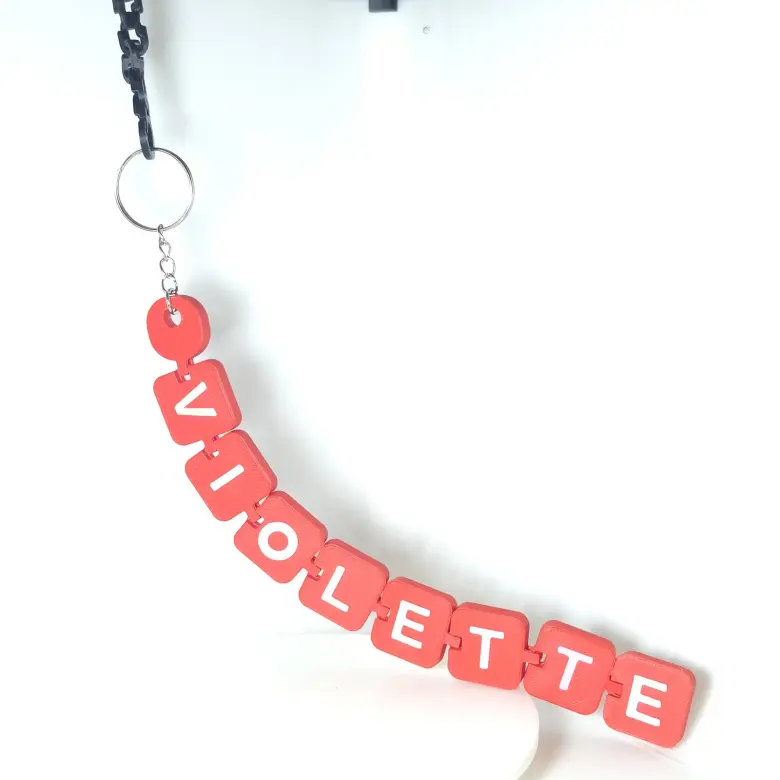 Llavero articulado rojo con letras blancas que forman el nombre Violette y argolla metálica.